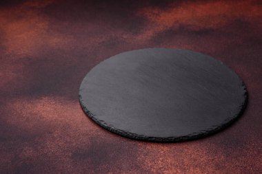 Empty ceramic round plate on dark textured concrete background. Cutlery, preparation for dinner