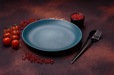 Empty ceramic round plate on dark textured concrete background. Cutlery, preparation for dinner