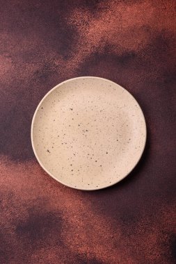 Empty ceramic round plate on dark textured concrete background. Cutlery, preparation for dinner