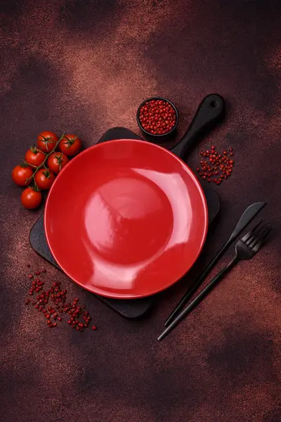 Empty ceramic round plate on dark textured concrete background. Cutlery, preparation for dinner