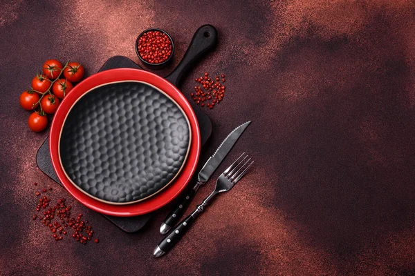 Empty ceramic round plate on dark textured concrete background. Cutlery, preparation for dinner