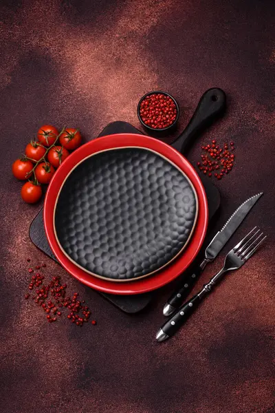 Empty ceramic round plate on dark textured concrete background. Cutlery, preparation for dinner