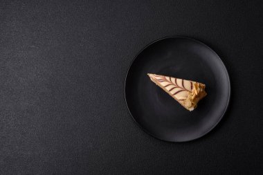 Fındıklı ve kremalı lezzetli pastadan bir parça koyu beton arka planda.