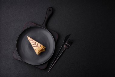 Fındıklı ve kremalı lezzetli pastadan bir parça koyu beton arka planda.