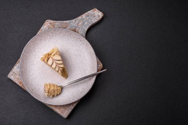 Fındıklı ve kremalı lezzetli pastadan bir parça koyu beton arka planda.