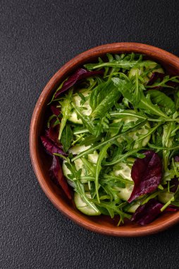Lezzetli taze salata roka, ıspanak, salatalık ve kiraz domatesli koyu beton kaplama seramik bir tabakta.