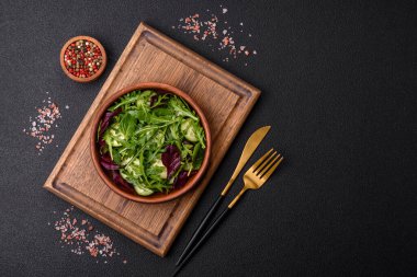 Lezzetli taze salata roka, ıspanak, salatalık ve kiraz domatesli koyu beton kaplama seramik bir tabakta.