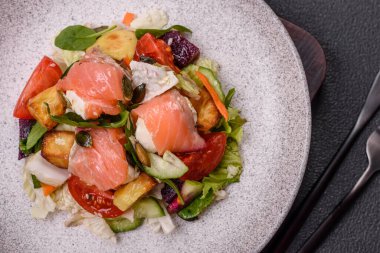 Somon, domates, salatalık, salatalık, otlar, kabak çekirdekleri, seramik tabakta tuz ve baharatlarla dolu lezzetli bir salata.