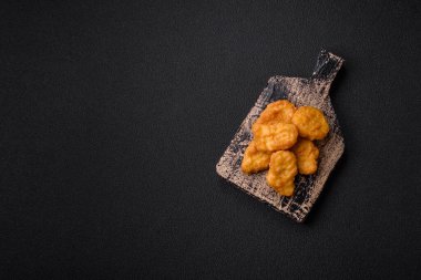 Delicious fresh crispy chicken nuggets on a dark concrete background. Unhealthy food, fast food