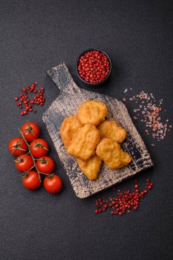 Delicious fresh crispy chicken nuggets on a dark concrete background. Unhealthy food, fast food