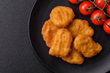 Delicious fresh crispy chicken nuggets on a dark concrete background. Unhealthy food, fast food