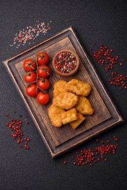 Delicious fresh crispy chicken nuggets on a dark concrete background. Unhealthy food, fast food