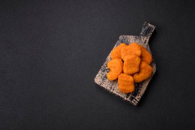 Delicious fresh crispy chicken nuggets on a dark concrete background. Unhealthy food, fast food