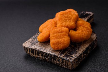 Delicious fresh crispy chicken nuggets on a dark concrete background. Unhealthy food, fast food