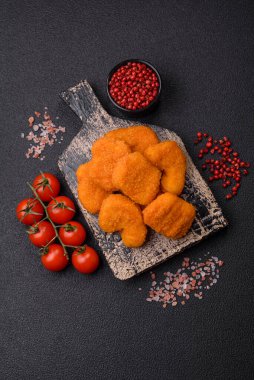 Delicious fresh crispy chicken nuggets on a dark concrete background. Unhealthy food, fast food