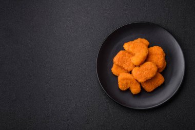 Delicious fresh crispy chicken nuggets on a dark concrete background. Unhealthy food, fast food