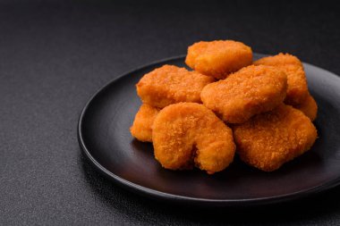 Delicious fresh crispy chicken nuggets on a dark concrete background. Unhealthy food, fast food