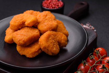 Delicious fresh crispy chicken nuggets on a dark concrete background. Unhealthy food, fast food