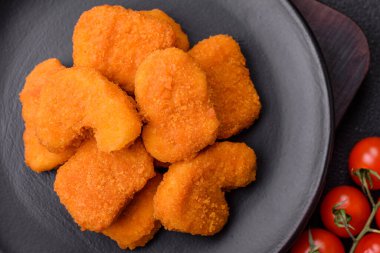 Delicious fresh crispy chicken nuggets on a dark concrete background. Unhealthy food, fast food