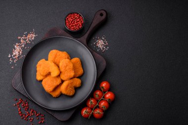 Delicious fresh crispy chicken nuggets on a dark concrete background. Unhealthy food, fast food