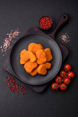 Delicious fresh crispy chicken nuggets on a dark concrete background. Unhealthy food, fast food