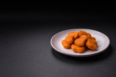 Delicious fresh crispy chicken nuggets on a dark concrete background. Unhealthy food, fast food