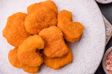 Delicious fresh crispy chicken nuggets on a dark concrete background. Unhealthy food, fast food