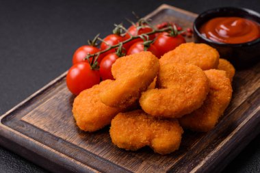Delicious fresh crispy chicken nuggets on a dark concrete background. Unhealthy food, fast food
