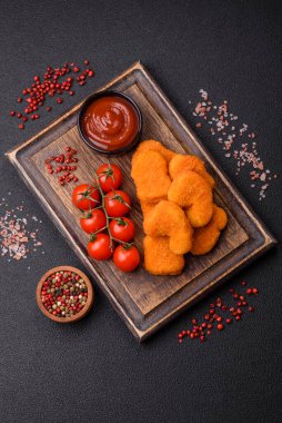 Delicious fresh crispy chicken nuggets on a dark concrete background. Unhealthy food, fast food