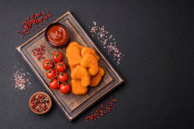 Delicious fresh crispy chicken nuggets on a dark concrete background. Unhealthy food, fast food