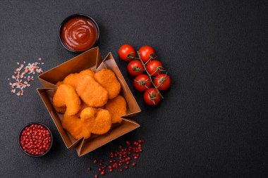 Delicious fresh crispy chicken nuggets on a dark concrete background. Unhealthy food, fast food