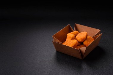 Delicious fresh crispy chicken nuggets on a dark concrete background. Unhealthy food, fast food