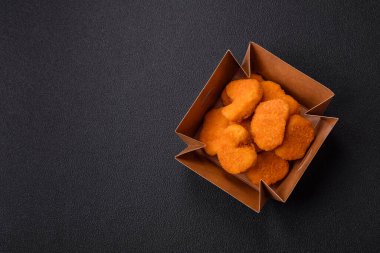 Delicious fresh crispy chicken nuggets on a dark concrete background. Unhealthy food, fast food