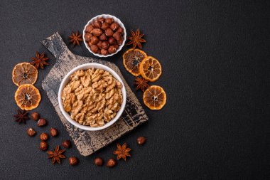 Lezzetli taze kabuklu çiğ cevizler seramik tabakta koyu beton arka planda.