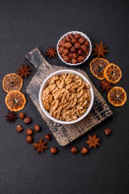 Lezzetli taze kabuklu çiğ cevizler seramik tabakta koyu beton arka planda.