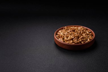 Lezzetli taze kabuklu çiğ cevizler seramik tabakta koyu beton arka planda.