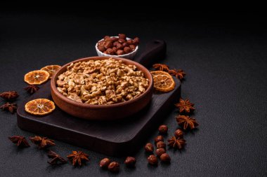 Lezzetli taze kabuklu çiğ cevizler seramik tabakta koyu beton arka planda.