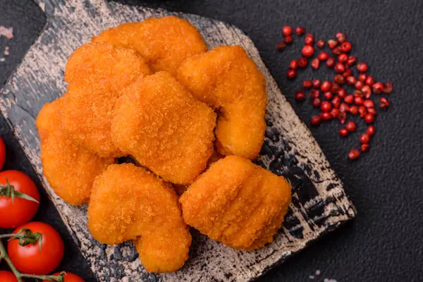 Delicious fresh crispy chicken nuggets on a dark concrete background. Unhealthy food, fast food