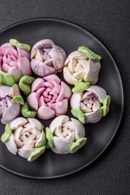 Lale tomurcukları şeklinde güzel, lezzetli marşmelovlar. Koyu beton bir arka planda.