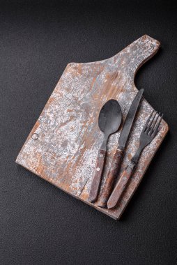 Çatal bıçak, bıçak ve kaşık koyu dokulu beton arka planda. Mutfak eşyaları ve aksesuarları.
