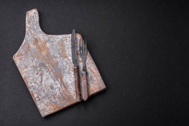 Çatal bıçak, bıçak ve kaşık koyu dokulu beton arka planda. Mutfak eşyaları ve aksesuarları.