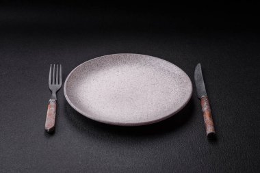 Çatal bıçak, bıçak ve kaşık koyu dokulu beton arka planda. Mutfak eşyaları ve aksesuarları.