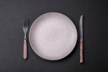 Çatal bıçak, bıçak ve kaşık koyu dokulu beton arka planda. Mutfak eşyaları ve aksesuarları.
