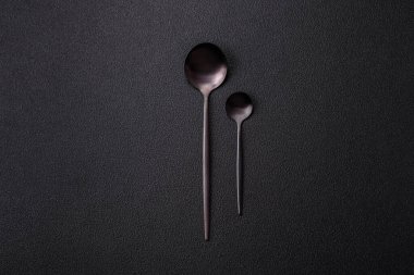 Çatal bıçak, bıçak ve kaşık koyu dokulu beton arka planda. Mutfak eşyaları ve aksesuarları.