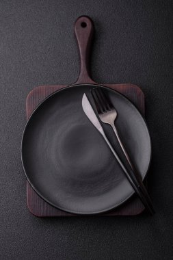 Çatal bıçak, bıçak ve kaşık koyu dokulu beton arka planda. Mutfak eşyaları ve aksesuarları.
