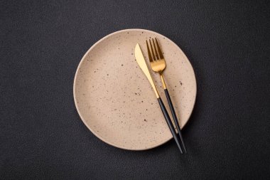 Çatal bıçak, bıçak ve kaşık koyu dokulu beton arka planda. Mutfak eşyaları ve aksesuarları.