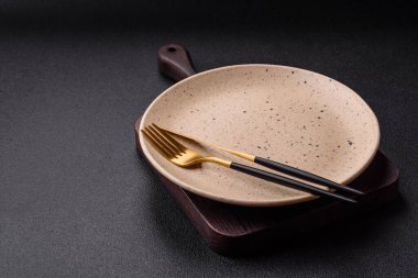 Çatal bıçak, bıçak ve kaşık koyu dokulu beton arka planda. Mutfak eşyaları ve aksesuarları.