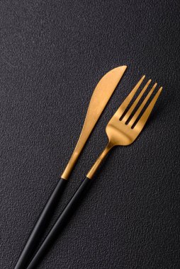 Çatal bıçak, bıçak ve kaşık koyu dokulu beton arka planda. Mutfak eşyaları ve aksesuarları.