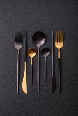 Çatal bıçak, bıçak ve kaşık koyu dokulu beton arka planda. Mutfak eşyaları ve aksesuarları.