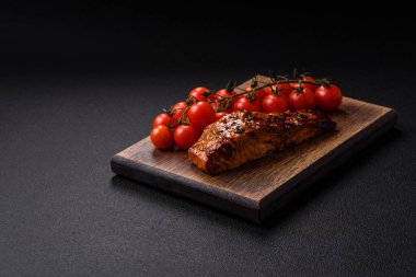 Sos ve susamlı lezzetli kırmızı somon balığı, koyu beton arka planda baharatlar ve otlar.